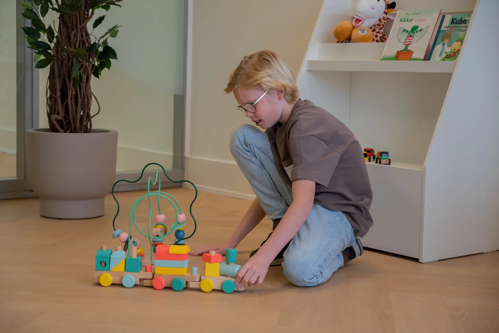 Jongen speelt met houten speelgoed in de kinderhoek van de wachtkamer
