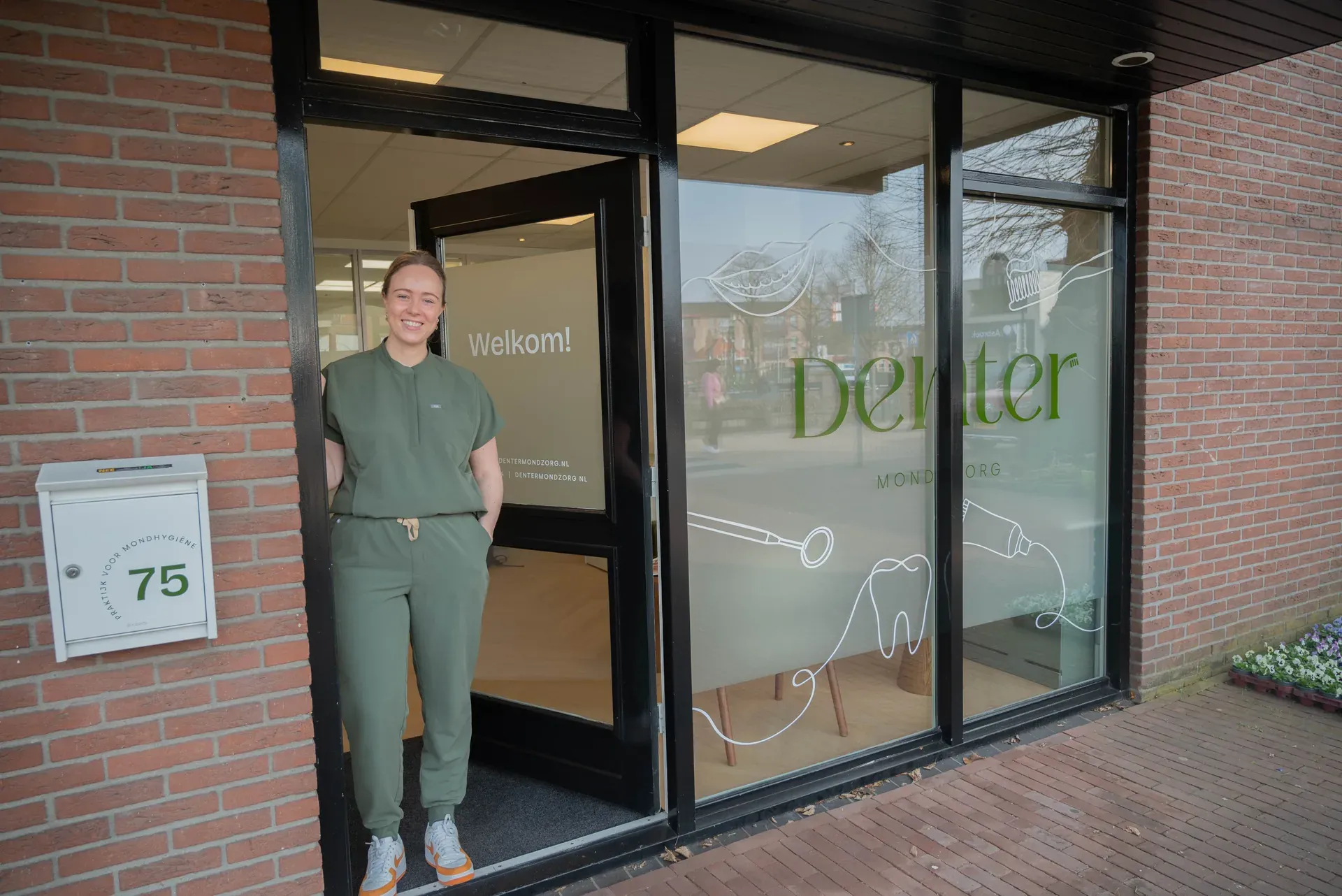 Jonne staat lachend in de deuropening van de praktijk aan de Dorpsstraat 75
