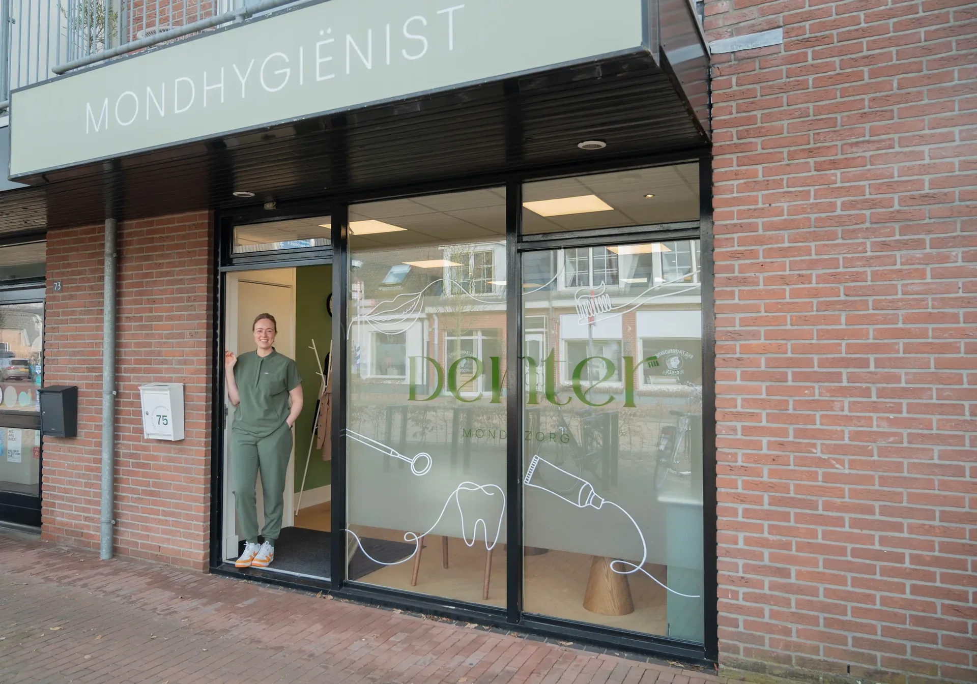 Gevel van DENTER mondzorg aan de Dorpsstraat 75 in Enter, met Jonne in de deuropening