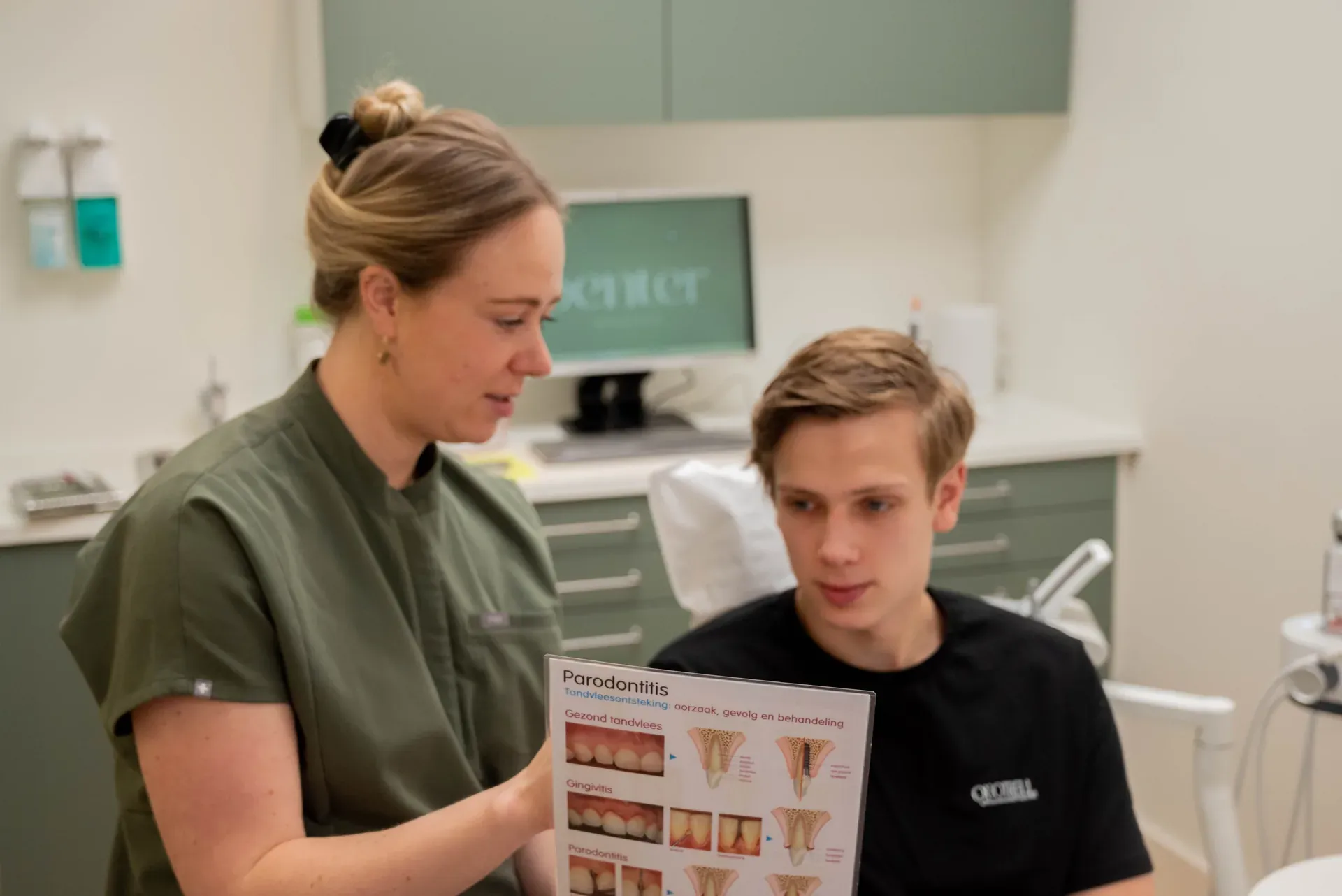 Jonne legt een jonge patiënt met een folder uit hoe tandvleesontsteking ontstaat