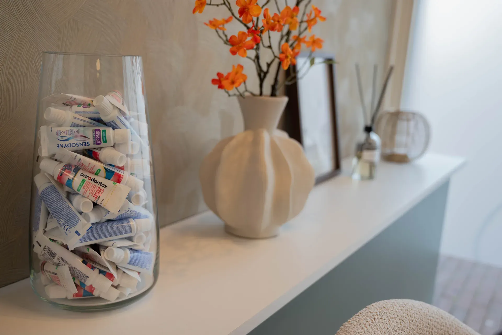 Dressoir in de wachtkamer met een vaas vol tandpastatubes en bloemen